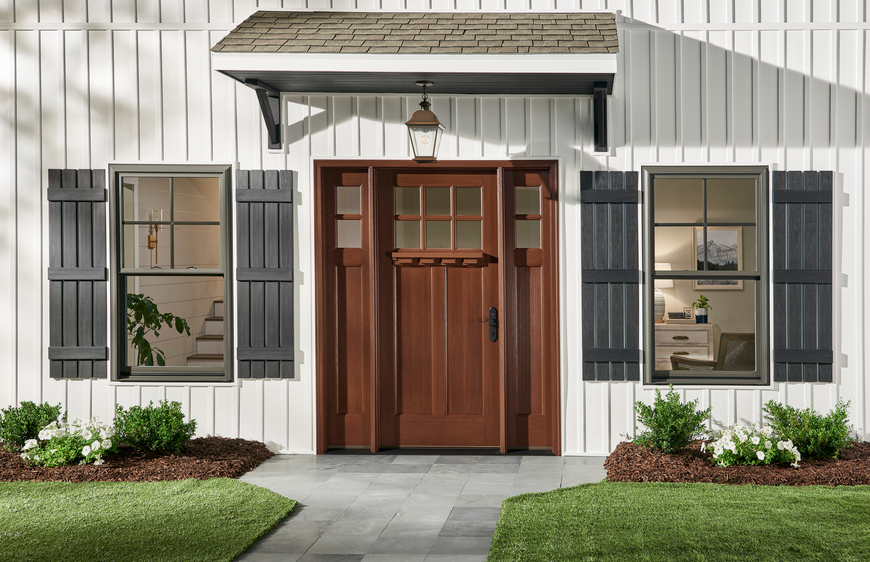 Farmhouse style home with dark wood entry door and white board and batten siding