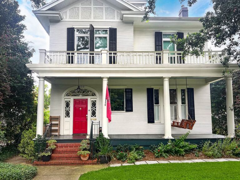 La style white home with front porch and red door